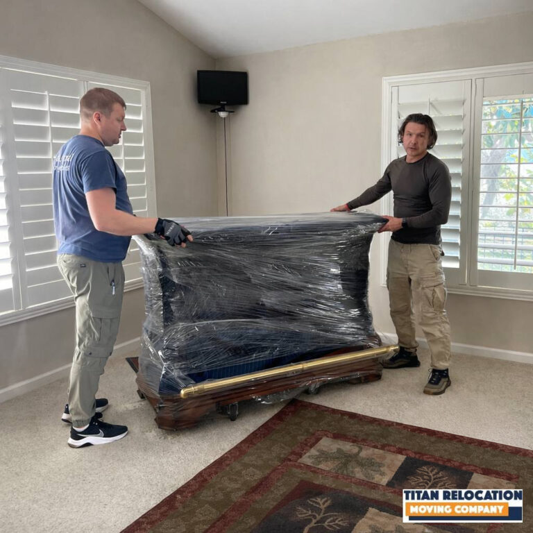 Titan Relocation movers handling a wrapped upright piano